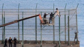 Des migrants subsahariens franchissent la barrière frontalière séparant le Maroc et Melilla